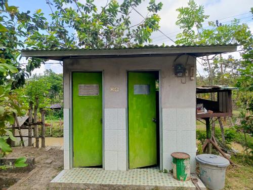 une maison extérieure verte et blanche avec deux portes dans l'établissement Montong Raden camping ground, à Midang