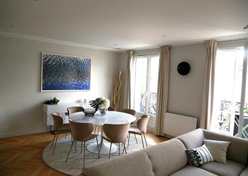 a living room with a couch and a table and chairs at Le Ciel de Paris - Montparnasse & Jardin du Luxembourg in Paris