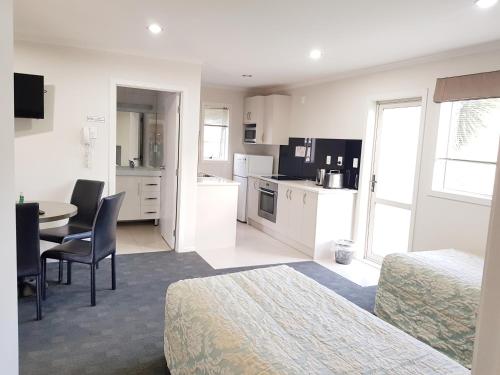 a room with two beds and a table and a kitchen at Phoenix Palm Motel in Auckland