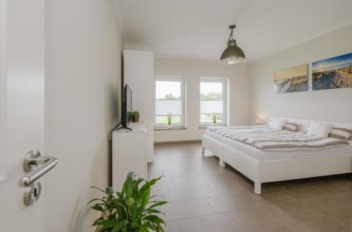 a white bedroom with a bed and a window at Ferienhaus Seeblick in Walchum