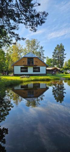 a house with a reflection in the water at Ozoli - Pirts / Viesunams in Alande
