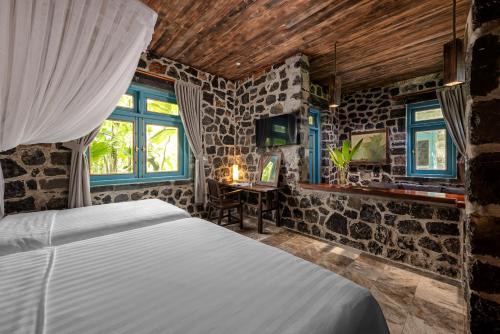 a bedroom with a bed in a room with stone walls at ChezCao Rice Field Ecolodge Ninh Binh in Ninh Binh