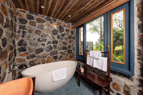 a bathroom with a tub and a stone wall at ChezCao Rice Field Ecolodge Ninh Binh in Ninh Binh