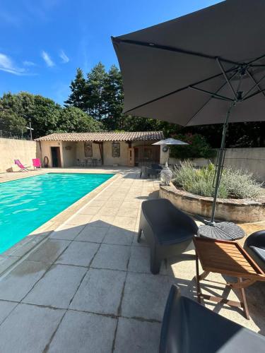 un patio avec un parasol et des chaises et une piscine dans l'établissement Mas le Canton, à Saint-Jean-du-Gard