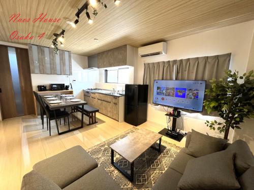 a living room with a couch and a table and a kitchen at Naos House Osaka 4 New Open 一軒家貸切 in Osaka