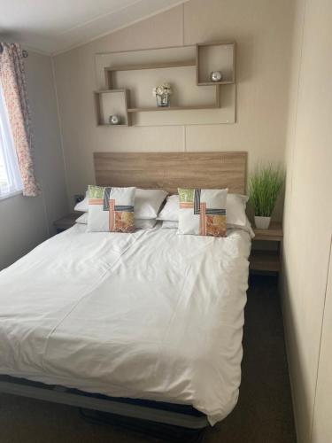 a bedroom with a bed with white sheets and pillows at Hughes Holiday Home in St Osyths in Jaywick Sands