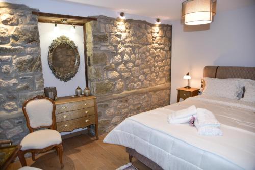 a bedroom with a bed and a stone wall at Elen's Suites Pramanta in Pramanta