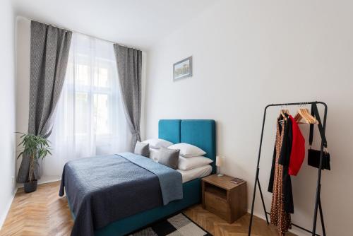 Un dormitorio con una cama azul y una ventana en Prague - Karlin Apartments, en Praga