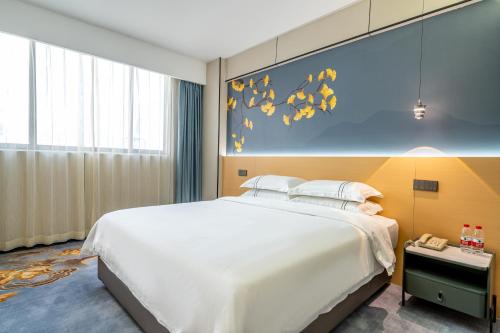 a bedroom with a large white bed and a blue wall at WAIFIDEN Hotel -Former Tokai Hotel - Xiaobei Metro Station - During the Canton Fair, there will be shuttle buses for transportation back and forth in Guangzhou