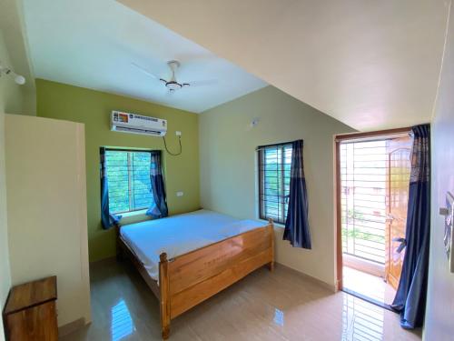 a bedroom with a bed and two windows at Atitheya Retreat in Bhubaneshwar