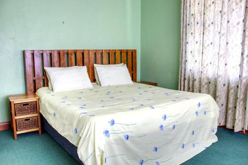 a bedroom with a large bed with a wooden headboard at Unique Bed and Breakfast in Harare