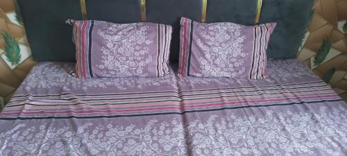 een paars bed met roze kussens en paarse lakens bij Midcity inn guest house in Ujjain