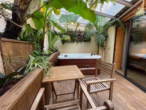 eine Terrasse mit einer Badewanne, einem Tisch und Stühlen in der Unterkunft myinsolite - Cocon Tropical, jacuzzi, énigme in Vauvert