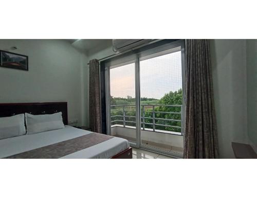 a bedroom with a bed and a window with a balcony at Hotel Hill View, Vadatalav, Gujarat in Hālol
