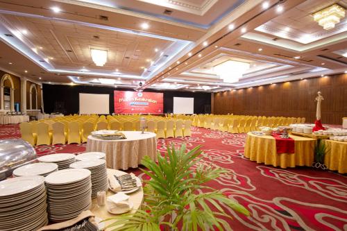 a banquet hall with white tables and yellow chairs at The Rich Jogja Hotel in Yogyakarta
