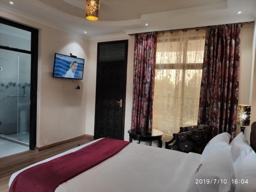 a hotel room with a bed and a tv on the wall at Kiikalloh Grand Resort in Machakos