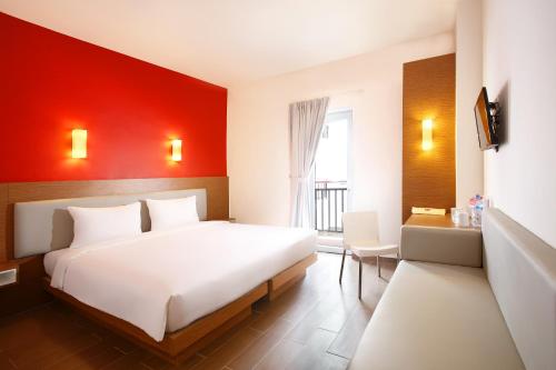 a bedroom with a white bed and a red wall at Amaris Hotel Muara Bungo - Jambi in Bebeko