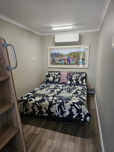 um quarto com uma cama com um edredão preto e branco em Almost Off Grid Tranquillity em Katherine