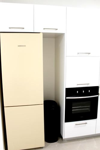a white kitchen with a stove and a refrigerator at Beach Suite Israel- Private Jacuzzi Sea View Balcony, Off-Site Spa ביץ סוייט ישראל- ג'קוזי פרטי עם נוף ים, אפשרות לספא מוזל in Ashqelon