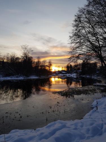 a sunset over a river in the snow at Riverside villa in Borlänge
