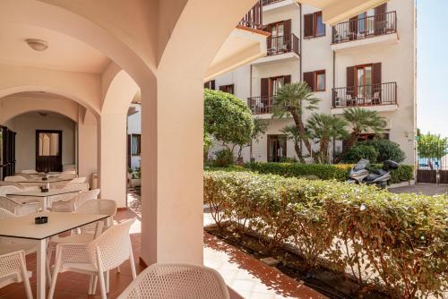 an outdoor patio with tables and chairs and a building at Hotel El Balear in Alghero