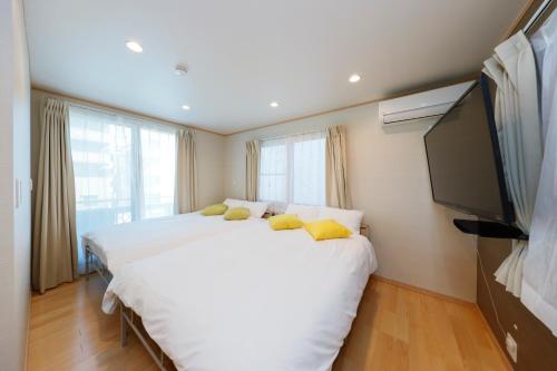 a bedroom with a large white bed and a flat screen tv at Convertel Daita by Tranova in Tokyo