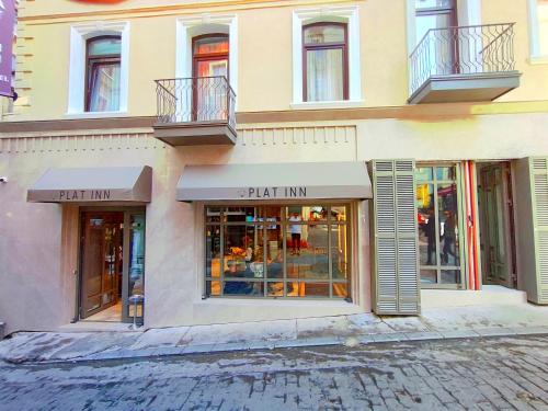 Plat Inn Hotel Taksim في إسطنبول: يوجد متجر أمام مبنى به نوافذ وشرفات