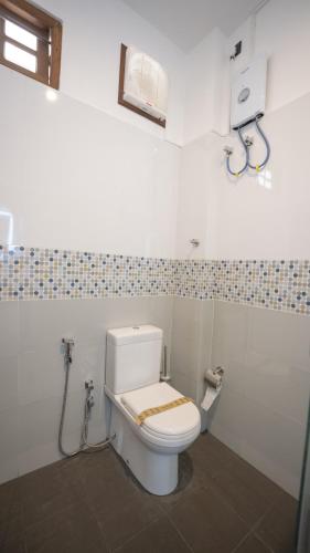 a bathroom with a white toilet in a room at JAMUNA VILLA in Jaffna
