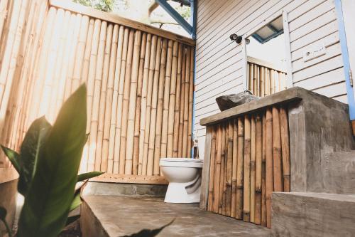 a bathroom with a toilet and a wooden fence at Casa Kapuas in Gili Trawangan
