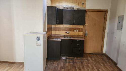 a small kitchen with black cabinets and a wooden floor at Al Makan Hotel by Al Azmy in Riyadh