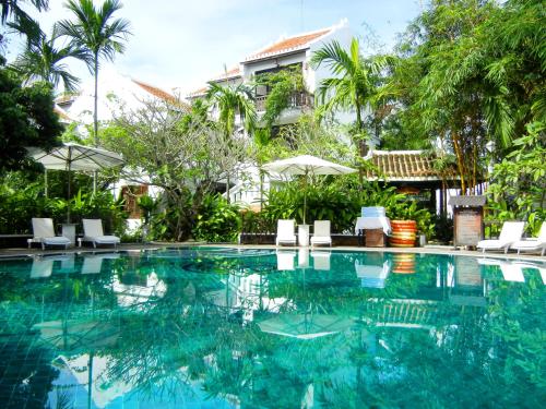 uma piscina num resort com cadeiras e árvores em Hoi An Ancient House Resort & Spa em Hoi An