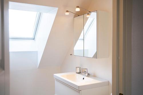a white bathroom with a sink and a mirror at Rymligt radhus med trädgård & parkering in Skurup