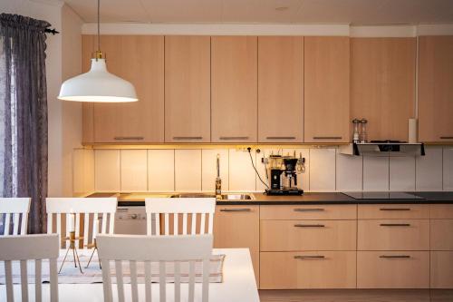 a kitchen with wooden cabinets and white chairs at Rymligt radhus med trädgård & parkering in Skurup