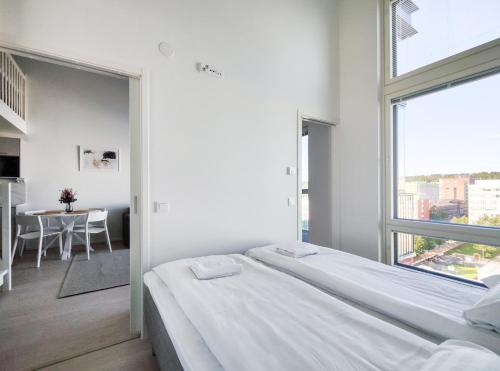 ein weißes Schlafzimmer mit einem Bett und einem großen Fenster in der Unterkunft 2ndhomes Tampere "Metso" Loft Apartment - Brand New Top Floor Apt that Hosts 6 in Tampere