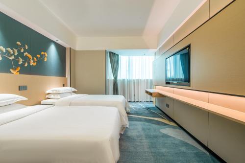 a hotel room with two beds and a flat screen tv at Wiffton Hotel -Former Tokai Hotel - Xiaobei Metro Station - Free shuttle bus during Canton Fair in Guangzhou