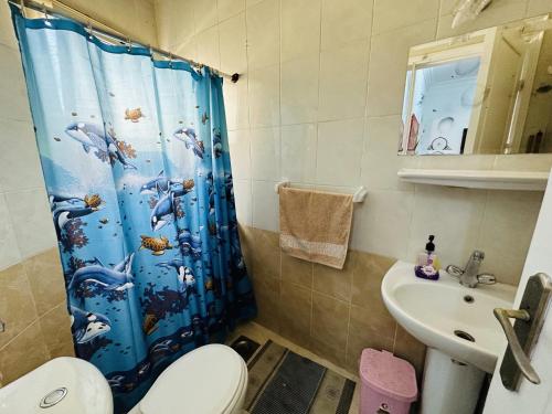 uma casa de banho com uma cortina de chuveiro azul e um lavatório. em Elephant House with Sea View em Hurghada