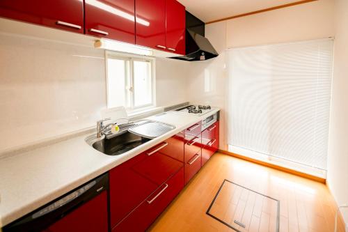 una cocina con armarios rojos y fregadero en Villa Futaba若松町 en Hakodate
