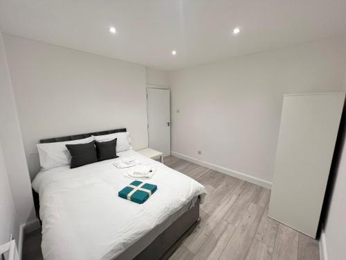 um quarto com uma cama branca e uma toalha verde em Beautifully refurbished 5-bed - Great Transport - Free Parking (sleeps 12) em Londres
