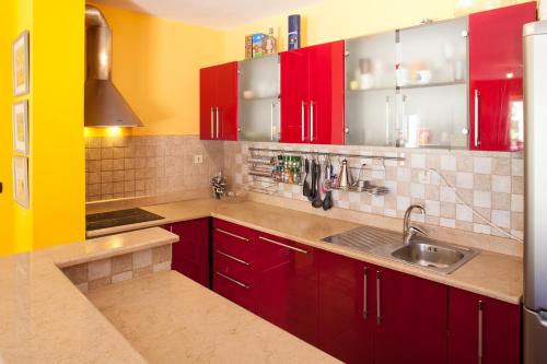 uma cozinha com armários vermelhos e um lavatório em Apartments Tino em Makarska