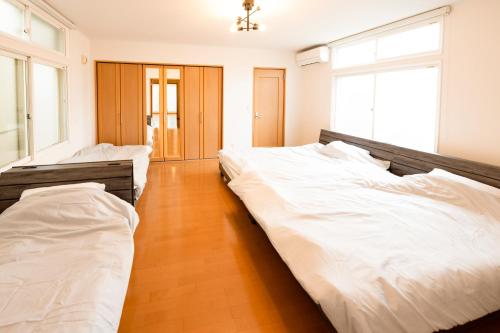 dwa łóżka w pokoju z białą pościelą w obiekcie Villa Futaba若松町 w mieście Hakodate