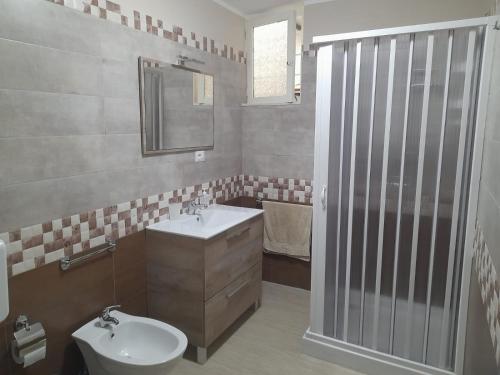 een badkamer met een wastafel, een toilet en een spiegel bij Casa Vacanza Marano in Mascali