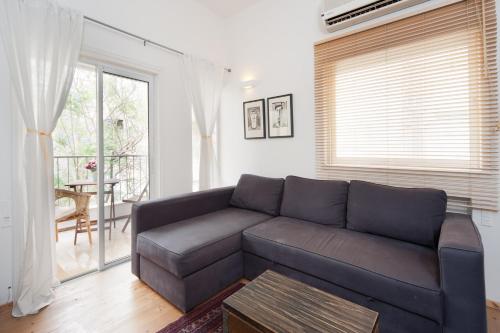ein Wohnzimmer mit einem Sofa und einem Tisch in der Unterkunft Stylish Apartments w Balcony in the Very Center by Sea N' Rent in Tel Aviv