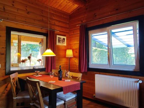 uma sala de jantar com uma mesa e duas janelas em Diemelsee Sudeck - Ein Ferienhäuschen zum WOHLFÜHLEN em Diemelsee