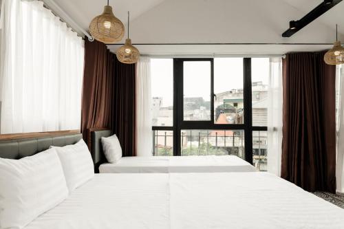 a bedroom with two beds and a large window at Tabalo Hostel Hanoi in Hanoi