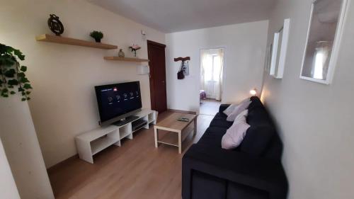 sala de estar con sofá negro y TV en VibesCoruña-Adelaida 41 en A Coruña