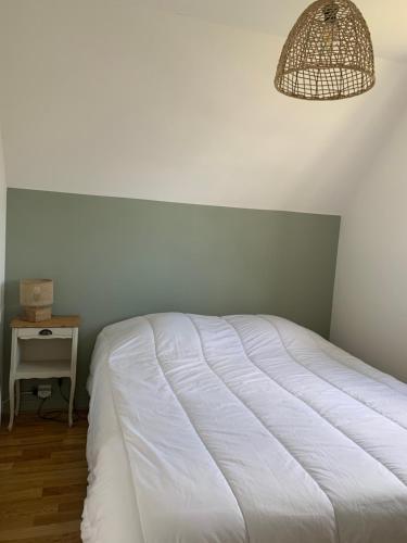 a bedroom with a white bed and a table at Maison Damgan 300m de la Plage in Damgan