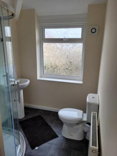 a bathroom with a toilet and a window at Cosy room in a stunning location in Llandrillo-yn-Rhôs
