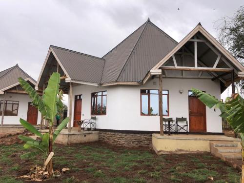 a white house with a black roof at Jua Manyara Lodge & Camp Site in Mto wa Mbu