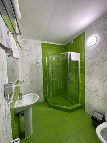 uma casa de banho verde com um chuveiro e um lavatório em Maestro em Ostroh