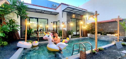 una mujer sentada en un unicornio en una piscina en Villa 68 4BR FREE PICK-UP AIRPORT & BILLIARDS CLOSE TO MY KHE BEACH, en Da Nang